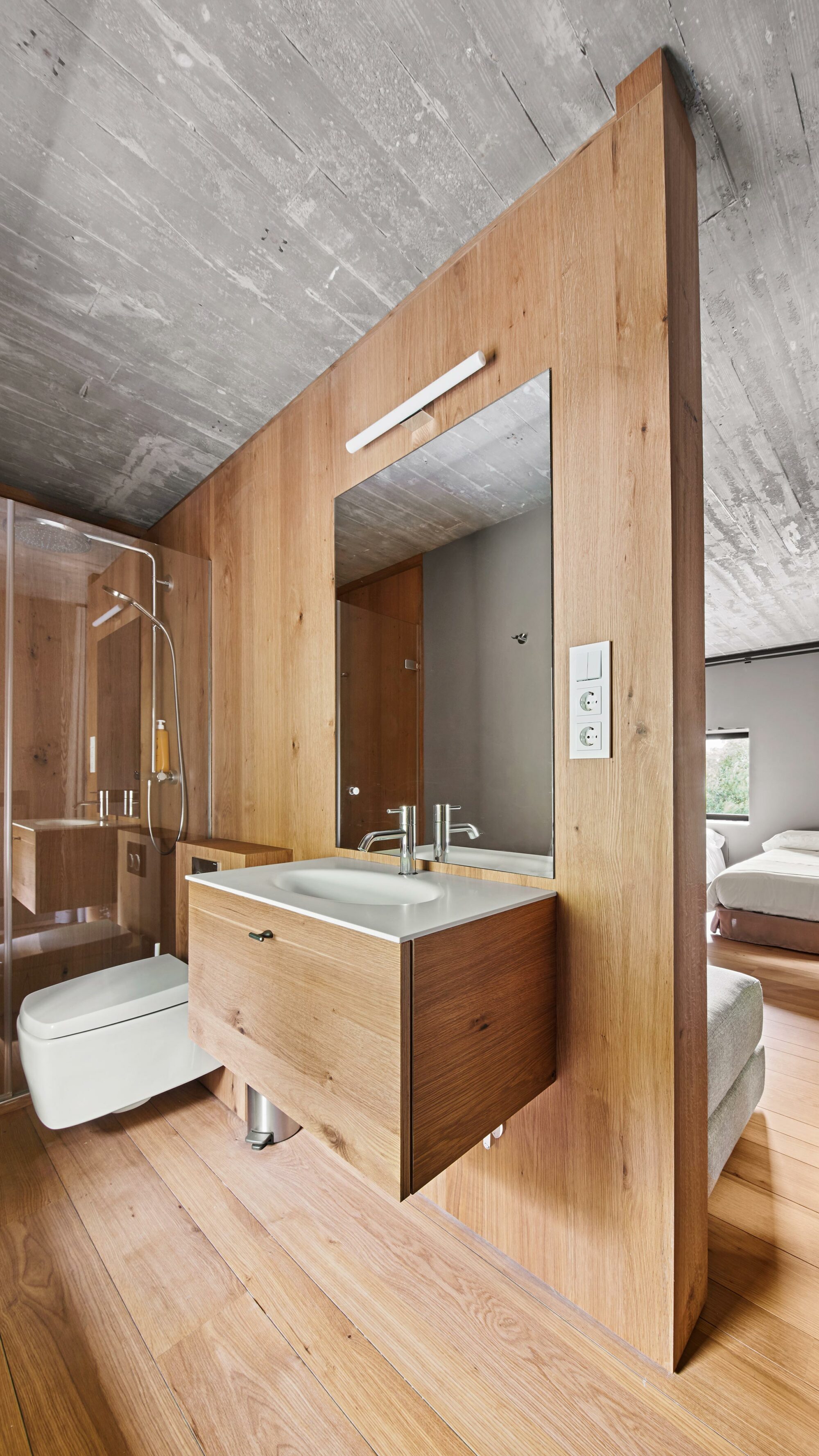 I rivestimenti interni e pavimenti in legno resistenti all'acqua Parklex Prodema creano continuità dalla camera da letto al bagno della casa rurale Landaburu Borda