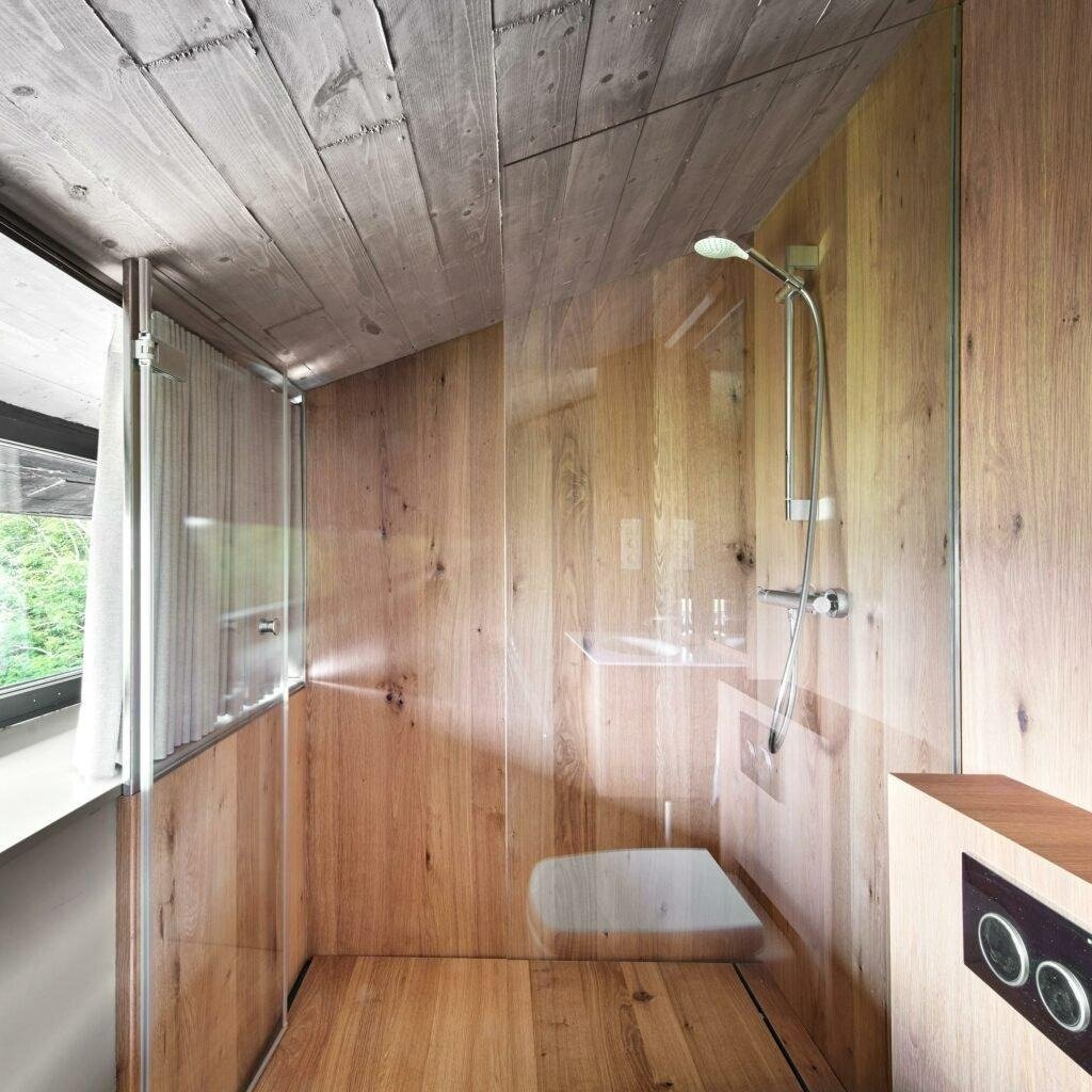 The water-resistant wood panels by Parklex Prodema create continuity across the walls, floors, furniture, and shower cabins in the Landaburu Borda rural house.